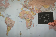 world map and man holding a send me sign 
