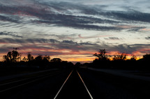 light from a sunset reflecting on train tracks