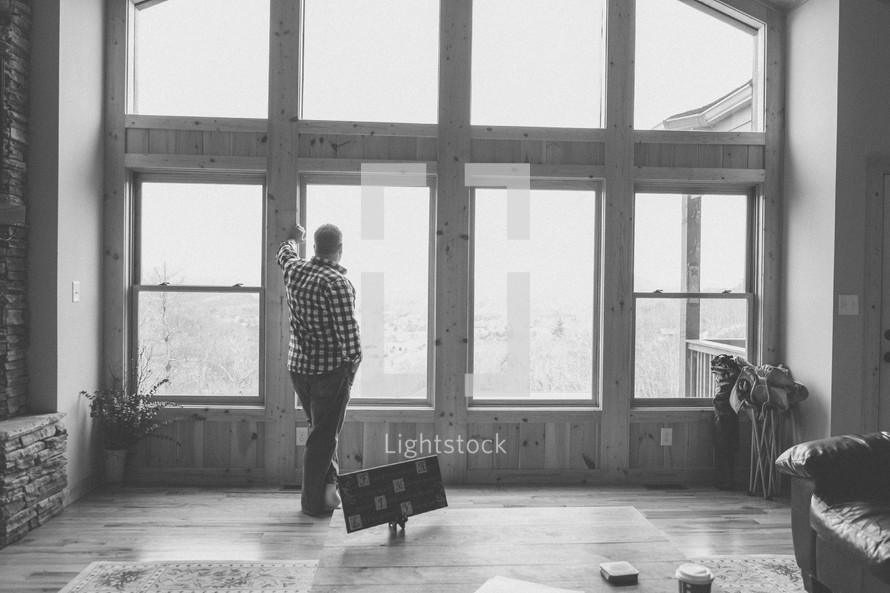 man standing looking out a window in thought 