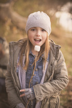 girl child eating marshmallows off a stick 