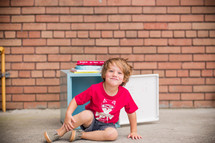 a child sitting in front of a school locker 