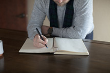 a man writing his New Year's resolutions in a journal 