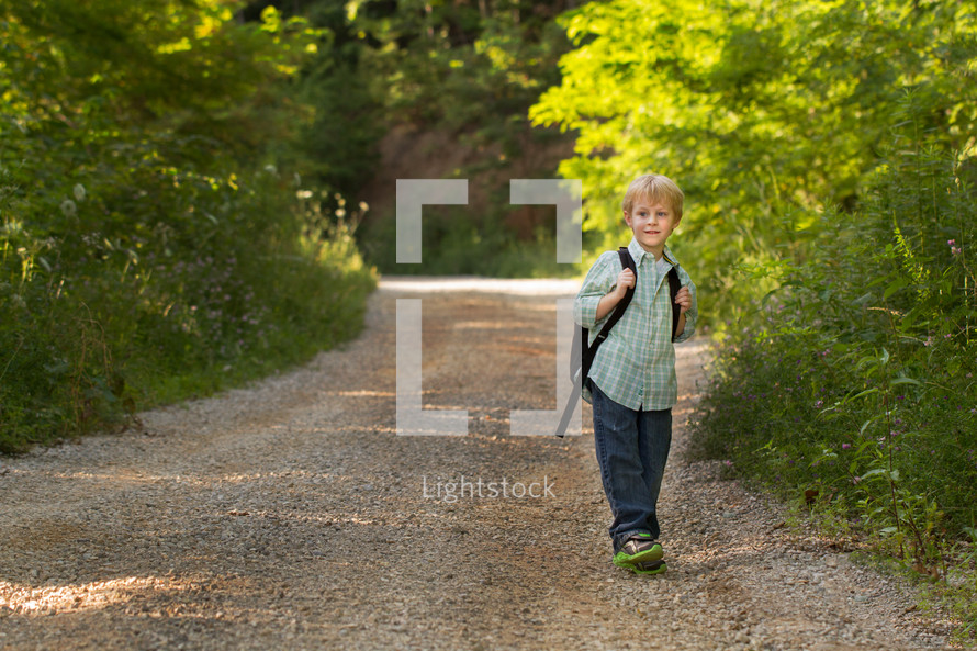 child with a backpack on a dirt road 