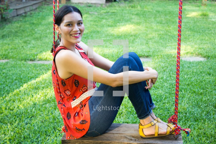 a woman sitting on a rope swing smiling 