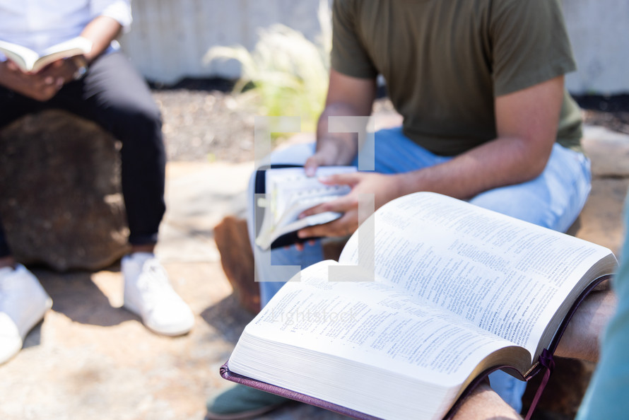 A small group Bible study sitting together outdoors. 