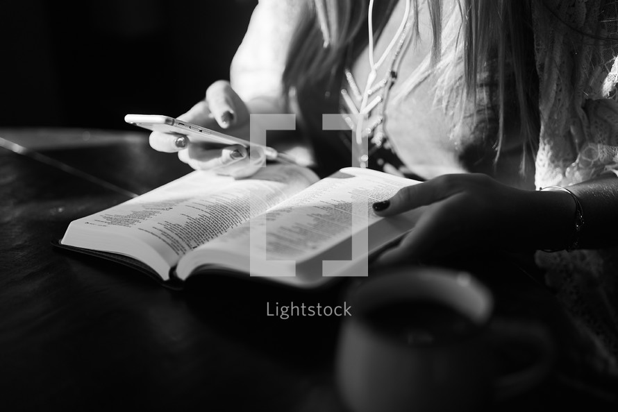 a woman reading a Bible and holding a cellphone 