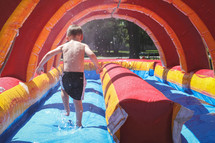 boy on a bounce house water slide 