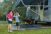 brother and sister standing next to a camper 