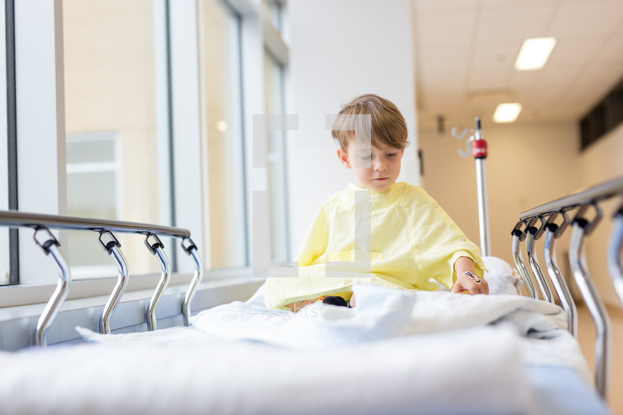 a boy child in a hospital gown in a hospital bed 