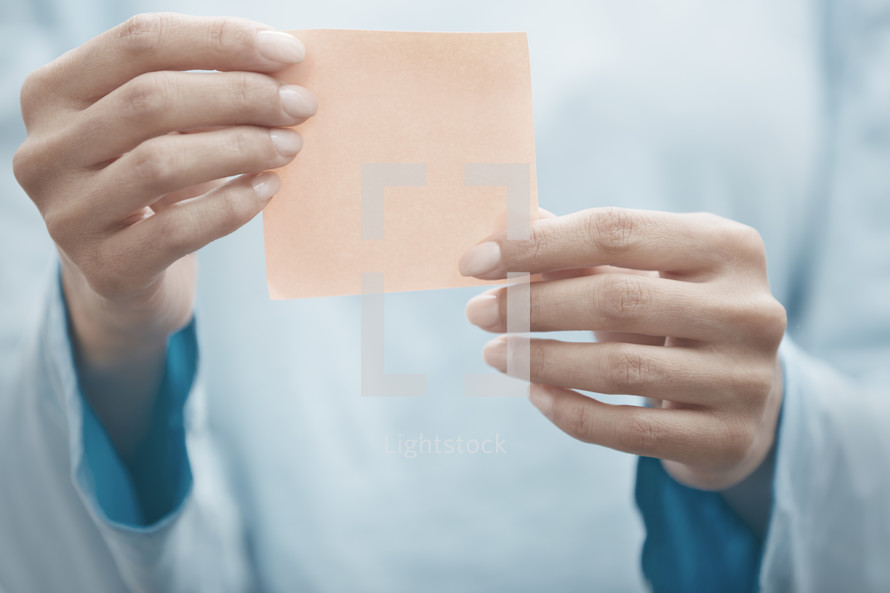 a woman holding up a blank sticky note 