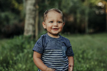 a toddler boy standing in grass 