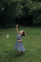 a toddler girl chasing bubbles in the grass 