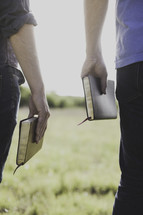 men holding Bibles at their sides outdoors 