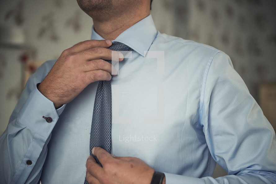 man adjusting his tie 