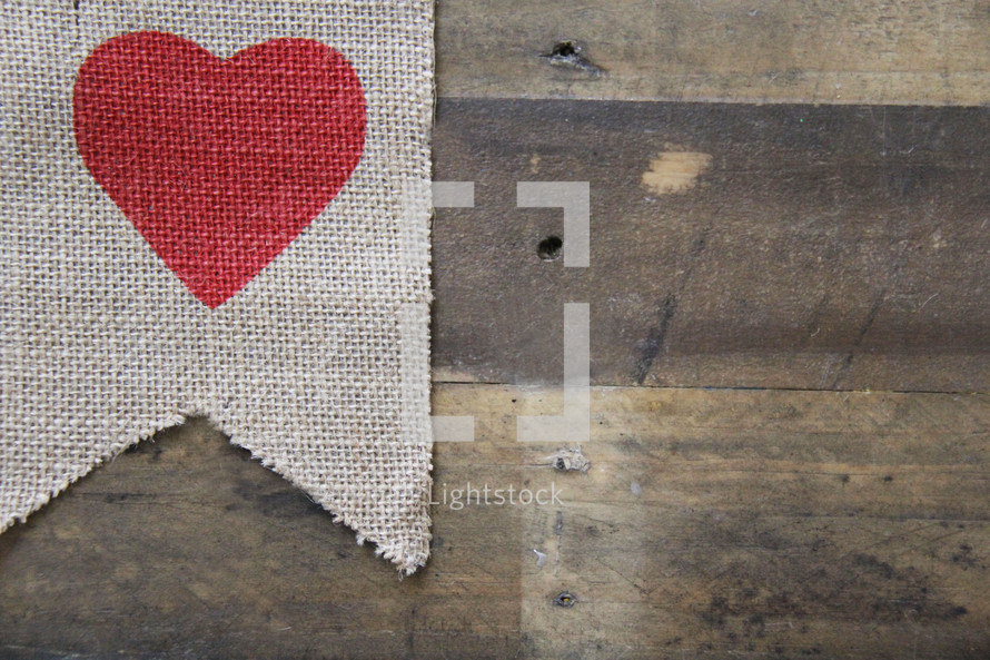 red heart on burlap on a wooden background 