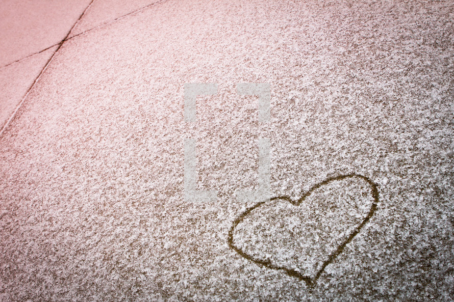 heart drawn in the snow on a sidewalk