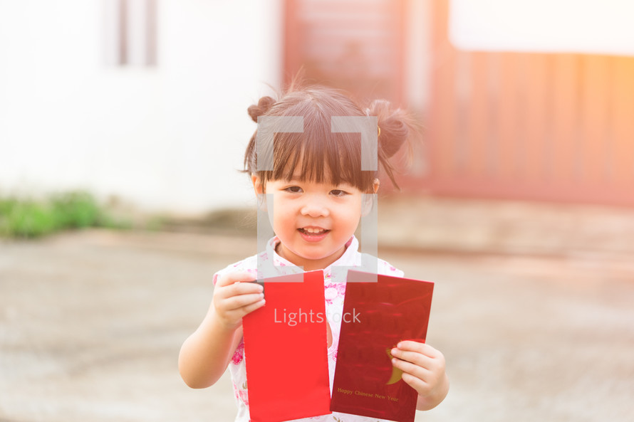Happy Little asian girl in chinese traditional dress smiling and holding red envelope.Happy chinese new year concept.