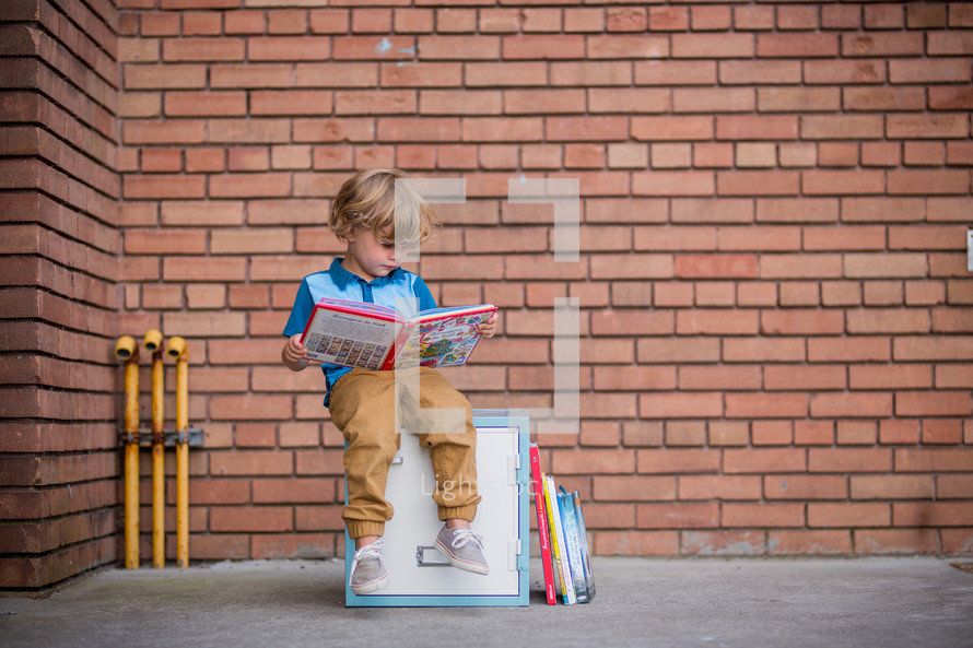 a child sitting on a locker reading a book 
