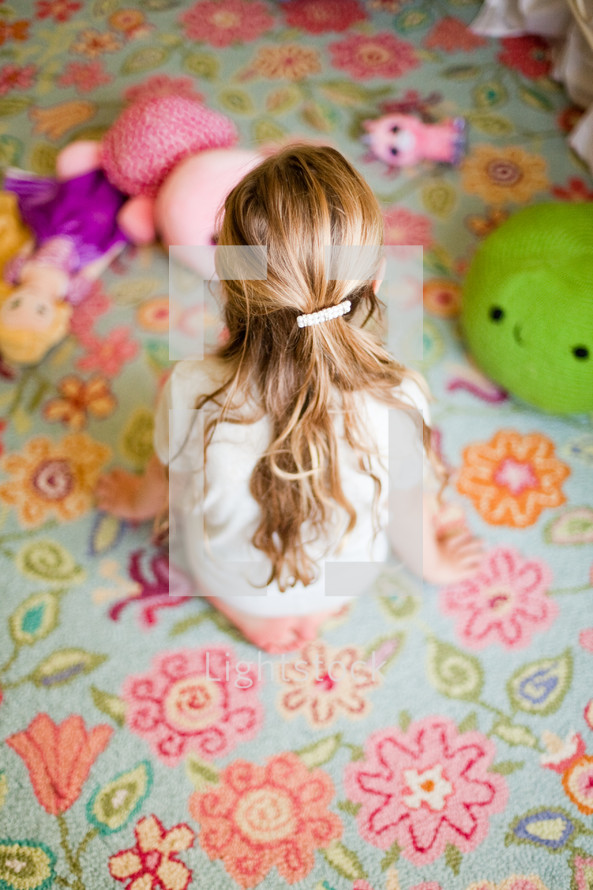 child sitting on a rug with toys 