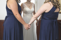 bride and bridesmaids holding hands in prayer 