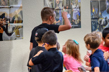 A youth leader leading a group of children in a line at VBS 