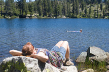 woman sleeping on a rock by a lake 