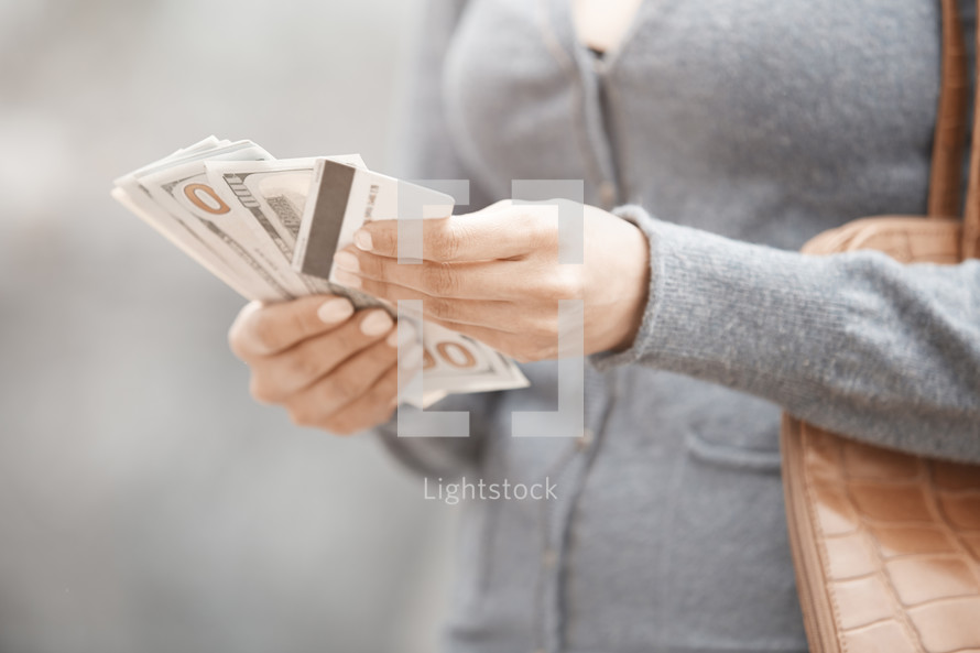 a woman holding cash and a credit card