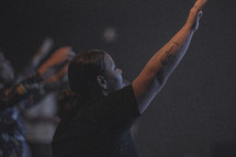 woman with hand raised at a worship service 