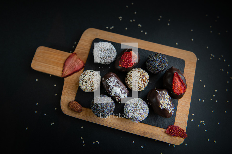 handmade sugar free and gluten free fruit and chocolate candies on a wooden board and black background
