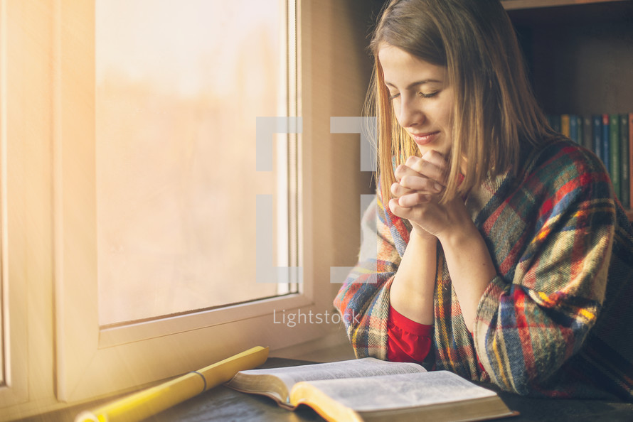 young woman praying over an opened Bible