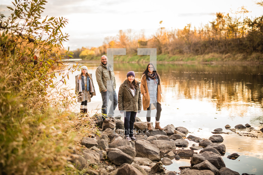 family standing on riverbanks 