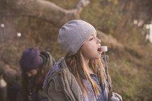 a girl child eating marshmallows off a stick 