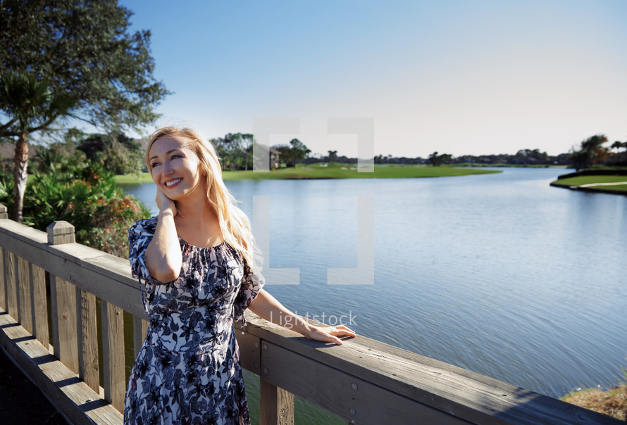 smiling woman standing on a wooden bridge 
