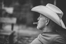 a man in a cowboy hat smoking a cigar 