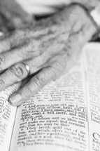 An elderly woman's hand on a Bible open to a passage about aging.