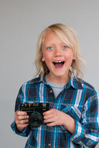 a happy young boy holding a camera 