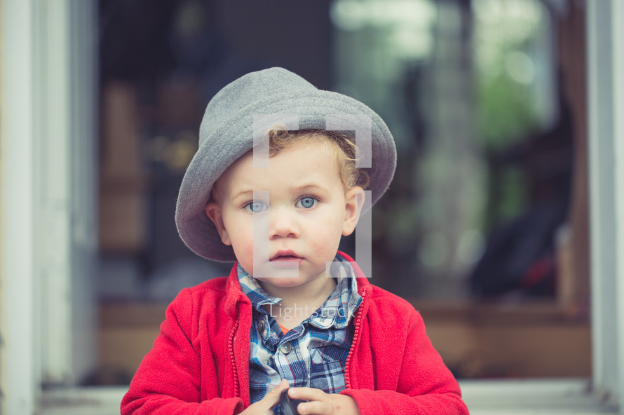 A little boy in a red coat and gray hat.