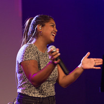 female singing and clapping on stage 