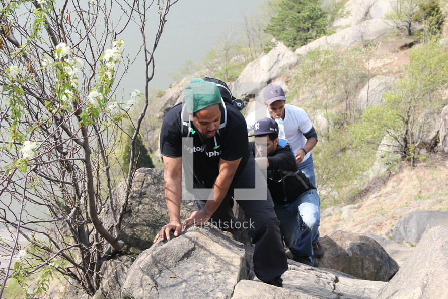 men climbing up a rocky terrain 