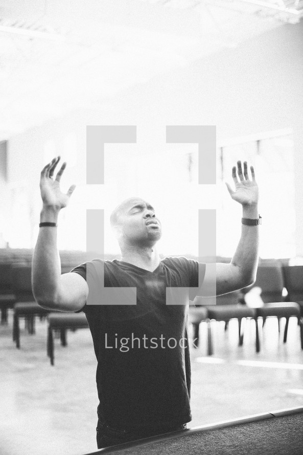 man with his hands raised in praise and worship to God in a church