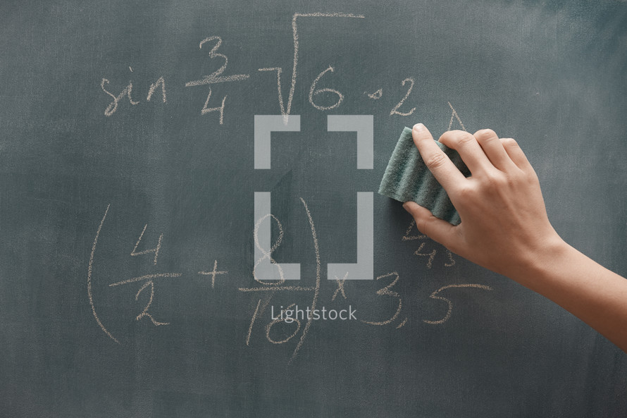 Hand of student studying mathematics and writing on a blackboard