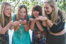 women blowing glitter off their hands