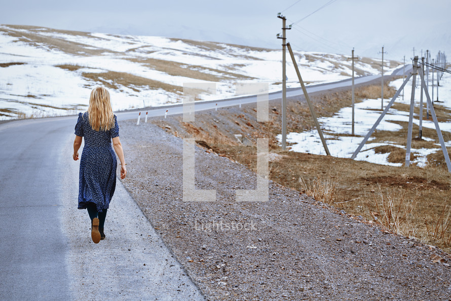 woman walking along a rural road alone 