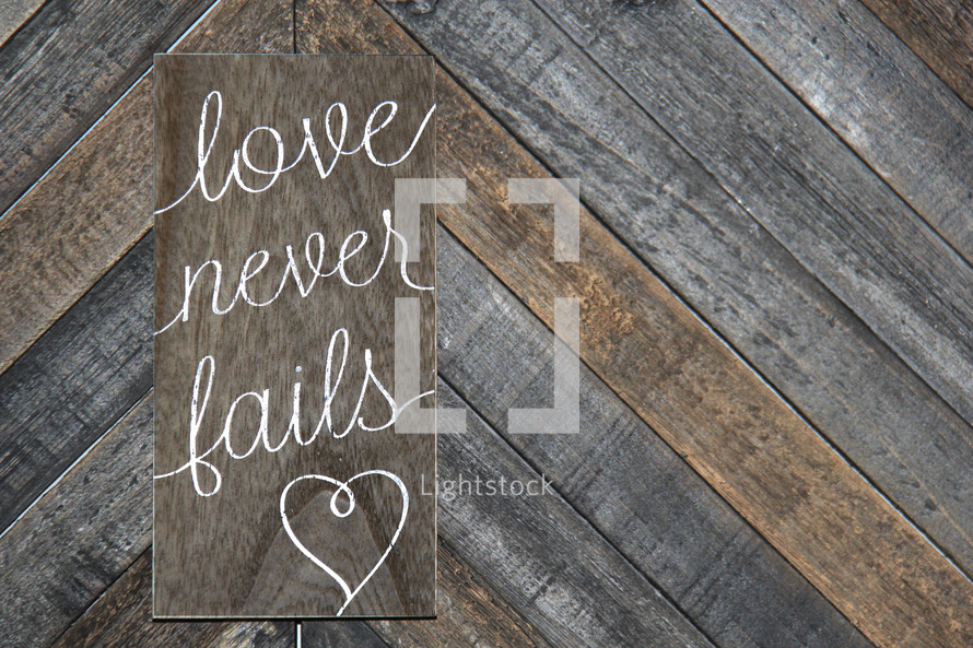 love never fails written on wooden background