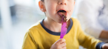 kid licking icing off of a knife 