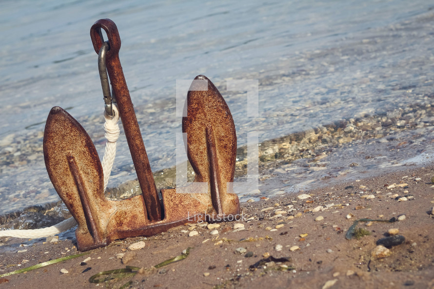 rusty anchor sitting upright on a shore