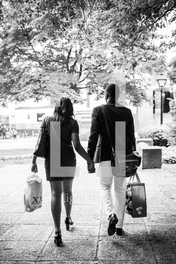a couple walking holding hands carrying shopping bags 