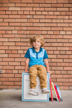 a child sitting on a locker with books 