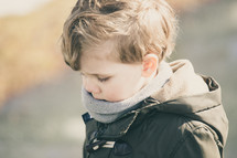 a boy child in a scarf and coat 