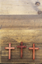 three wooden crosses on a wood floor 